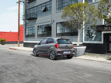 Kia Picanto geparkeerd in een stedelijke straat naast moderne gebouwen.