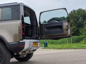 Een groene Land Rover Defender met de achterdeur open.