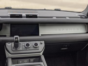 Binnenaanzicht van een Land Rover Defender met het dashboard, het infotainmentsysteem en de versnellingspook.