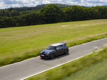 Een MINI John Cooper Works GP 2020 die over een landelijke weg rijdt met een onscherpe achtergrond die beweging aangeeft.