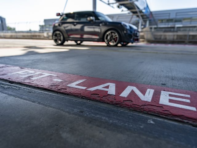 Zwarte MINI John Cooper Works GP 2020 geparkeerd bij een pitlane met focus op het bord "pitlane" op de grond.