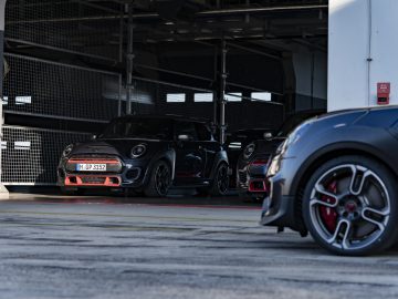 Een rij sportwagens geparkeerd in een garage, met een MINI John Cooper Works GP 2020 prominent op de voorgrond.