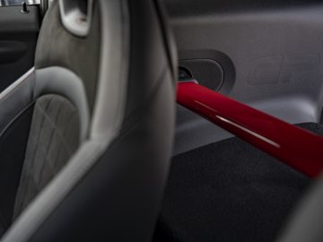 Binnenaanzicht van een voertuig waarbij de deur wordt benadrukt met het opschrift "MINI John Cooper Works GP 2020", met een rood accent en lederen bekleding.
