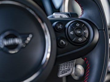 Close-up van een stuur met gemonteerde bedieningselementen en schakelpeddels, met het logo van het luxe automerk MINI John Cooper Works GP 2020.