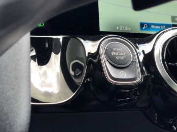 Binnenaanzicht van een Mercedes-Benz GLA met de startknop van de motor en glanzend zwarte bekleding.