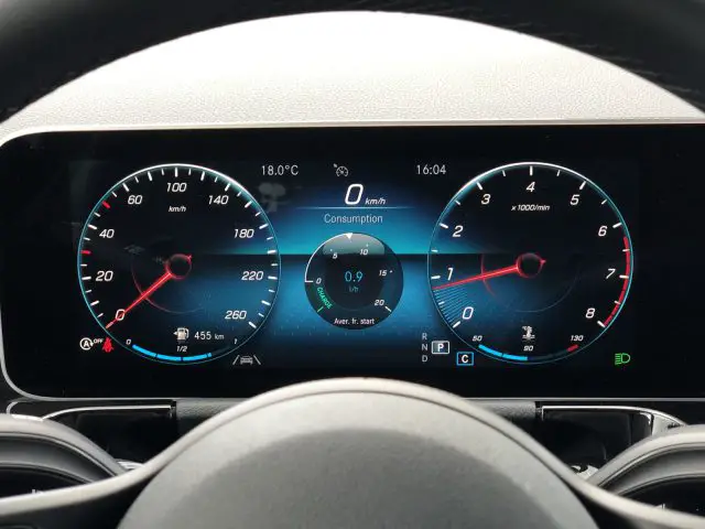 Een digitaal dashboard van een Mercedes-Benz GLA met de snelheidsmeter, toerenteller, brandstofverbruik en buitentemperatuur.