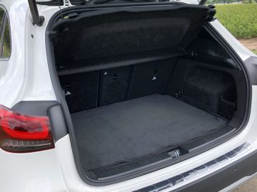 Open kofferbak van een witte Mercedes-Benz GLA met een schone en lege laadruimte.