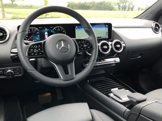 Binnenaanzicht van een moderne Mercedes-Benz GLA met het stuur, het dashboard, de digitale displays en de middenconsole.