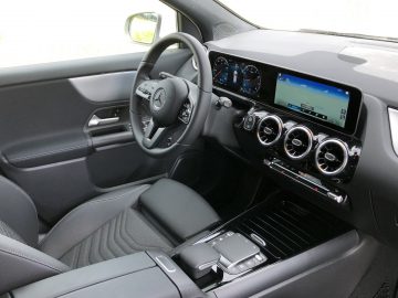 Binnenaanzicht van een Mercedes-Benz GLA met stuur, digitaal dashboard en touchscreen op de middenconsole.