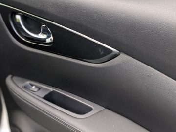 Close-up van het interieur van een Nissan Qashqai N-TEC autodeur met handgreep en bedieningspaneel.