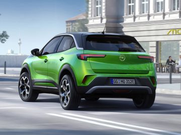 Groene Opel Mokka SUV rijden op een stedelijke straat.