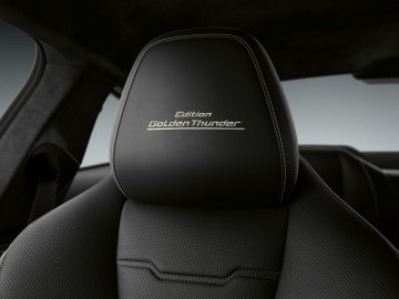 Close-up van een zwart lederen BMW 8 serie autostoelhoofdsteun met inscriptie "edition golden donder".
