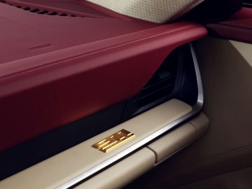 Close-up van het interieur van een Porsche 911 Targa 4S Heritage Design Edition met een rood en beige dashboard met metalen accenten.