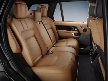 Luxueus Range Rover Fifty-interieur met lederen stoelen en uitzicht op de achterbank vanaf de zijdeur.