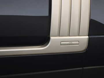 Close-up van het binnendeurpaneel van een Range Rover Fifty met beige afwerking en kenmerkend embleem.