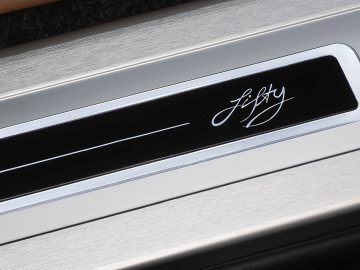 Close-up van de metalen instaplijsten van een voertuig met het logo 'Range Rover Fifty' opschrift.