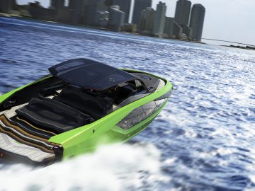 Supersnelle luxe Tecnomar voor Lamborghini 63-boot die vaart op blauw water nabij de skyline van een stad.