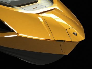 Close-up van een gele Tecnomar voor de voorkant van de Lamborghini 63, die het strakke ontwerp en de koplampdetails benadrukt.