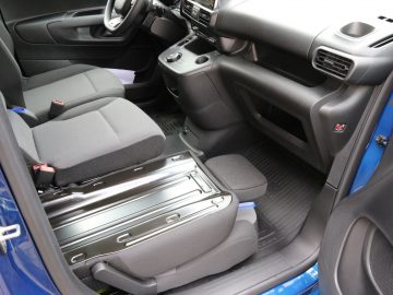 Weergave van een Toyota PROACE City-interieur met de voorstoelen en de middenconsole, met de nadruk op de opklapbare passagiersstoel.
