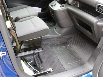 Binnenaanzicht van de Toyota PROACE City met een open deur met de nadruk op de bestuurdersstoel en het vloeroppervlak met een set automatten.