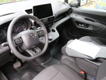 Binnenaanzicht van de bestuurderszijde van een Toyota PROACE City-voertuig, met het stuur, het dashboard en de middenconsole.