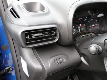 Toyota PROACE City-dashboard met een ventilatieopening, verschillende bedieningselementen en een gedeeltelijk zicht op de snelheidsmeter en brandstofmeter.