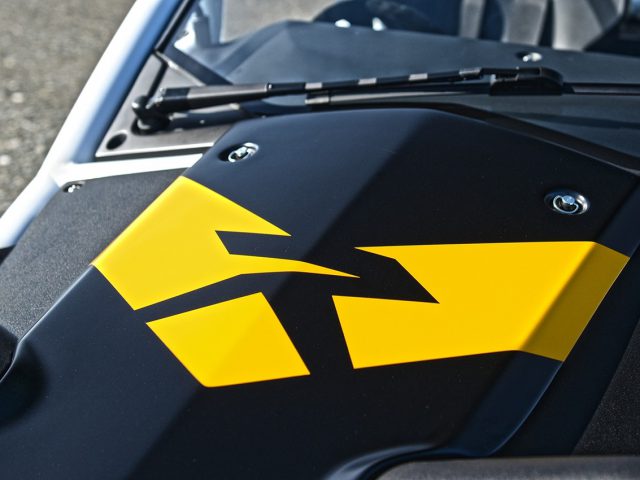 Close-up van een zwart-gele afbeelding op het Ariel Nomad R-paneel, waarschijnlijk onderdeel van een motorfiets of quad, met hoekige ontwerpelementen.