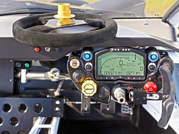 Close-up van het stuur en het digitale dashboard van een Ariel Nomad R met verschillende statistieken.