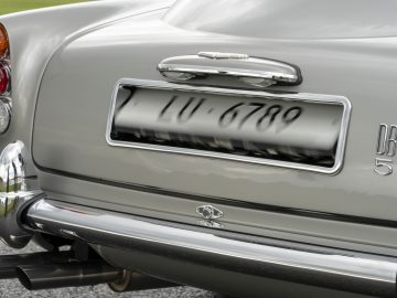 Close-up van het achterste gedeelte van een vintage Aston Martin DB5 Goldfinger Vervolg met een deel van de kentekenplaat, achterlichten en chromen details.