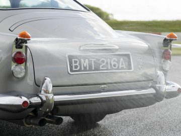 Achteraanzicht van een klassieke Aston Martin DB5 Goldfinger Vervolg met opvallende achterlichten en kentekenplaat "bmt 216a".
