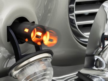 Close-up van de oplaadpoort van een Aston Martin DB5 Goldfinger Continuation met gloeiende lichten, ter illustratie van de auto die wordt opgeladen.