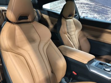 Binnenaanzicht van een BMW 4 Serie Coupé met bruin lederen stoelen, middenconsole en versnellingspook.