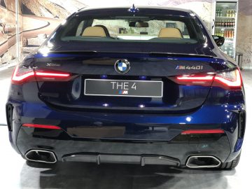 Achteraanzicht van een blauwe geparkeerde BMW 4 Serie Coupé, met de dubbele uitlaten en opvallende achterlichten.