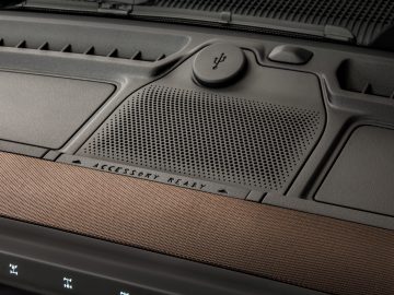 Close-up van een gestructureerd, professioneel luidsprekerrooster in een Ford Bronco met bedieningspictogrammen en een 'accessoire klaar'-label.