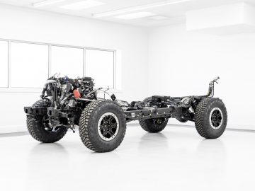 Een Ford Bronco-chassis tentoongesteld in een schone, goed verlichte showroom, met wielen, motor en aandrijflijn, die de interne mechanica van het voertuig demonstreren.