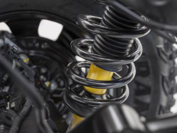 Close-up van een Ford Bronco-schokdemper en omliggende mechanische componenten, met zwarte en gele kleuren.