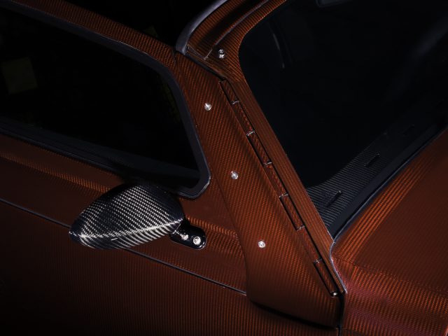 Een close-up van de bruinleren deur en koolstofvezelspiegel van een Donkervoort D8 GTO-JD70 Bare Naked Carbon Edition.