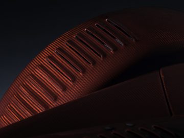 Close-up van een rode getextureerde sneaker met unieke ventilatiegaten, die gedetailleerd vakmanschap benadrukt, geïnspireerd op de Donkervoort D8 GTO-JD70 Bare Naked Carbon Edition.