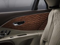 Luxe Bentley-interieur met gedetailleerde 3D-houten lambrisering, lederen bekleding en deurbediening.