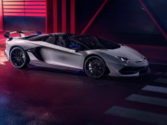 Een witte Lamborghini Aventador SVJ stond binnen geparkeerd met neonverlichting op de achtergrond.