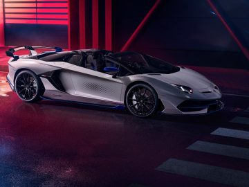 Een witte Lamborghini Aventador SVJ stond binnen geparkeerd met neonverlichting op de achtergrond.