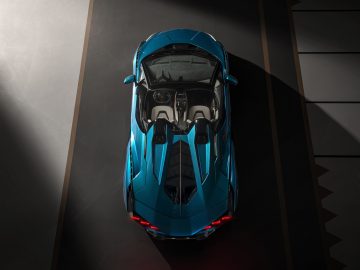 Luchtfoto van een blauwe Lamborghini Sián Roadster geparkeerd in een slecht verlichte ruimte, met de bovenkant en het strakke ontwerp met opvallende verlichting.
