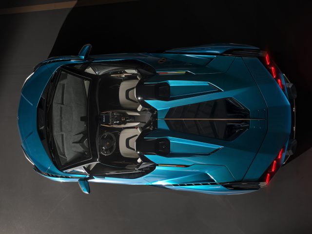 Bovenaanzicht van een blauwe Lamborghini Sián Roadster met open deuren geparkeerd op een grijze ondergrond.