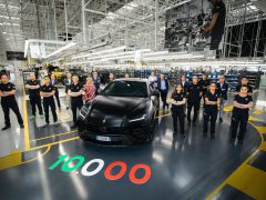 Arbeiders staan trots naast de 10.000ste zwarte Lamborghini in een moderne autofabriek.