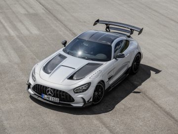 Luchtfoto van een witte Mercedes-AMG GT Black Series-sportwagen met een grote achtervleugel geparkeerd op een grijze betonnen ondergrond.