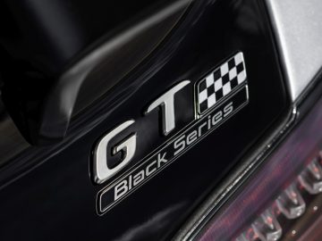 Close-up van een zwarte Mercedes-AMG GT Black Series-autobadge met een geblokt vlagontwerp.