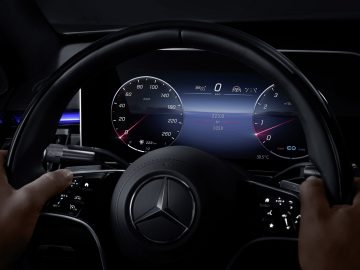 Bestuurdersaanzicht van een Mercedes-Benz S-Klasse stuurwiel en digitaal dashboard met snelheidsmeter en andere meters 's nachts.