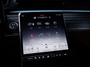 Het touchscreen van een Mercedes-Benz S-Klasse op de middenconsole waarop verschillende pictogrammen, zoals navigatie, telefoon en media, op een strak dashboard worden weergegeven.
