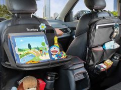 Auto-interieur met achterbank uitgerust met organizers met speelgoed, snacks en gadgets voor in de auto, waaronder een tablet met een cartoon.