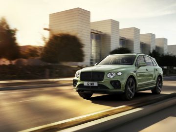 Een groene Bentley Bentayga luxe SUV die door een stadsstraat rijdt met bewegingsonscherpte die snelheid suggereert.
